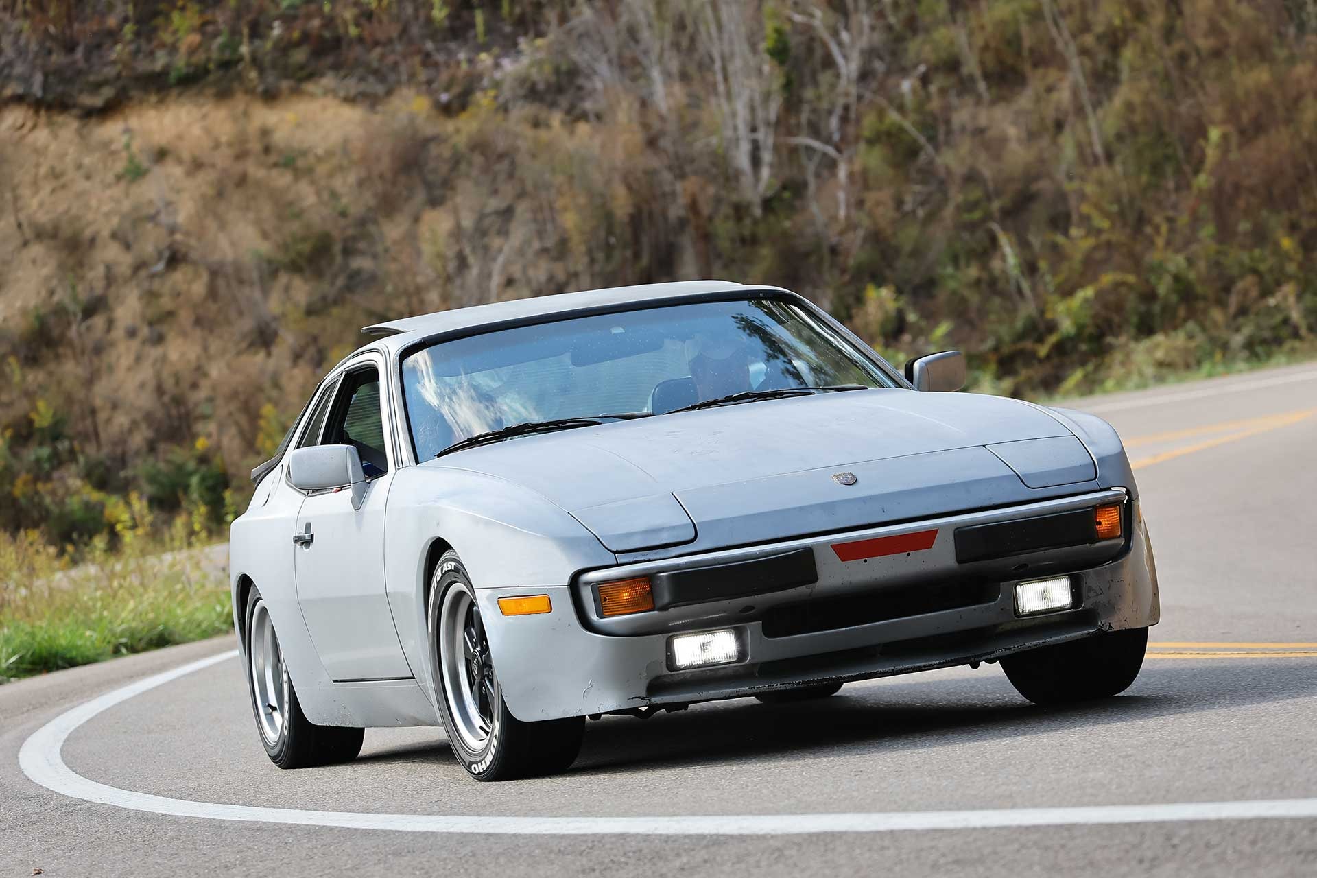 A gray 944 mid-corner on a mountain road